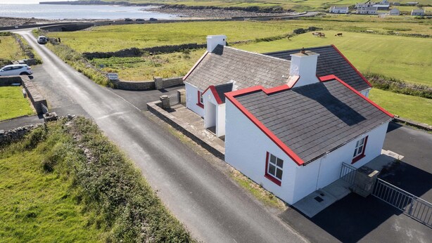 A coastal house with a red roof, white walls, and a paved driveway. - Pake's Cottage in Clahane (Liscannor)