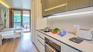 A modern kitchen with a built-in oven, a toaster, and a dining area with a sofa. - Il Mughetto Ski in / ski out (Bardonecchia)