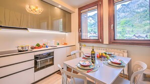 A modern kitchen with a dining area, large windows, and a view of mountains. - Il Mughetto Ski in / ski out (Bardonecchia)