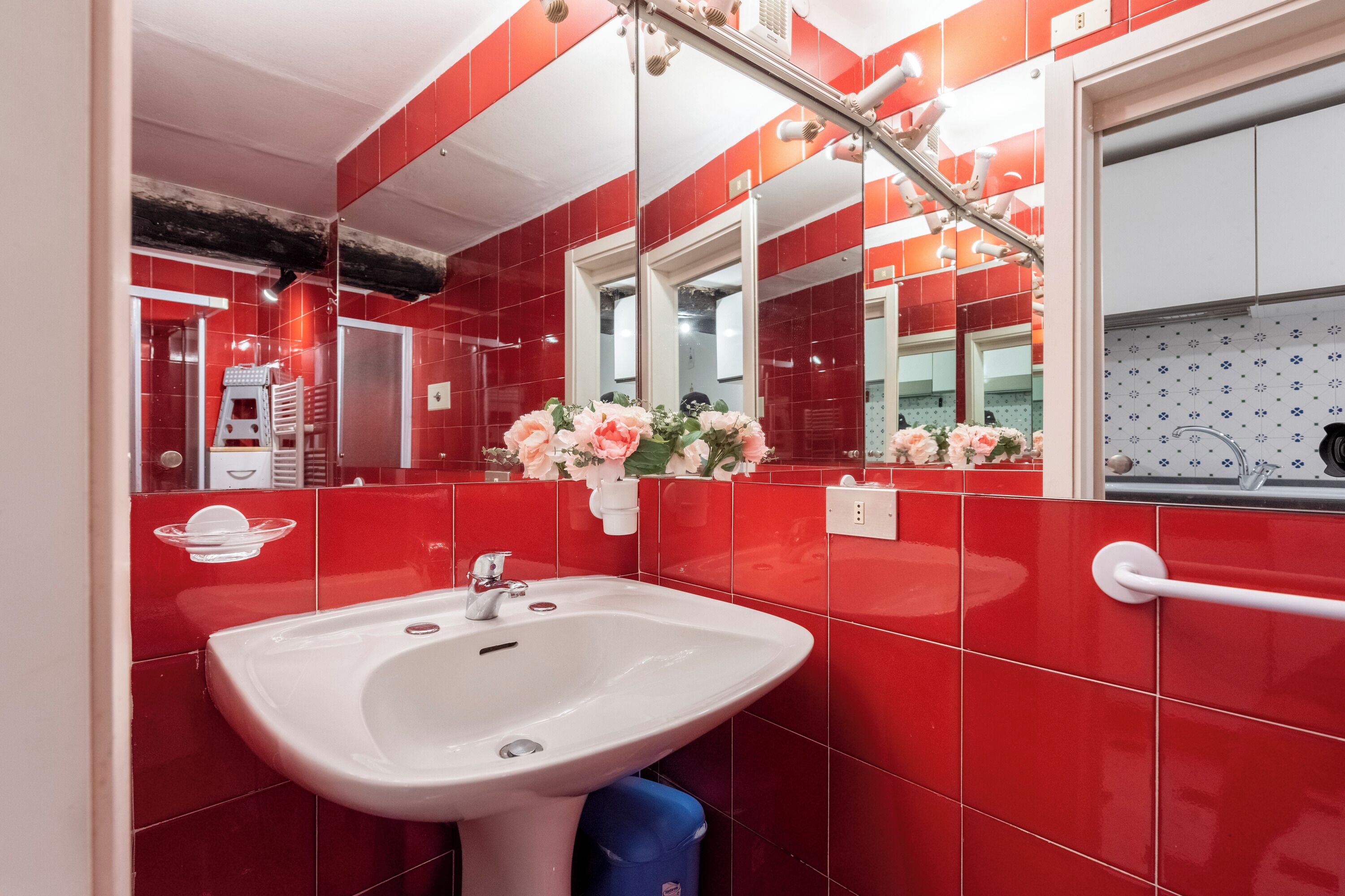 A bathroom with red tiles, a white sink, and a mirror.