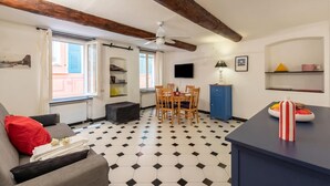 A living room with a sofa, a dining table, and a kitchen area with a TV. - Charming Apartment Historic Center Camogli (Camogli)