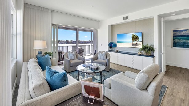 Un salon moderne doté d’une grande fenêtre, d’un téléviseur à écran plat et offrant une vue sur la plage.
