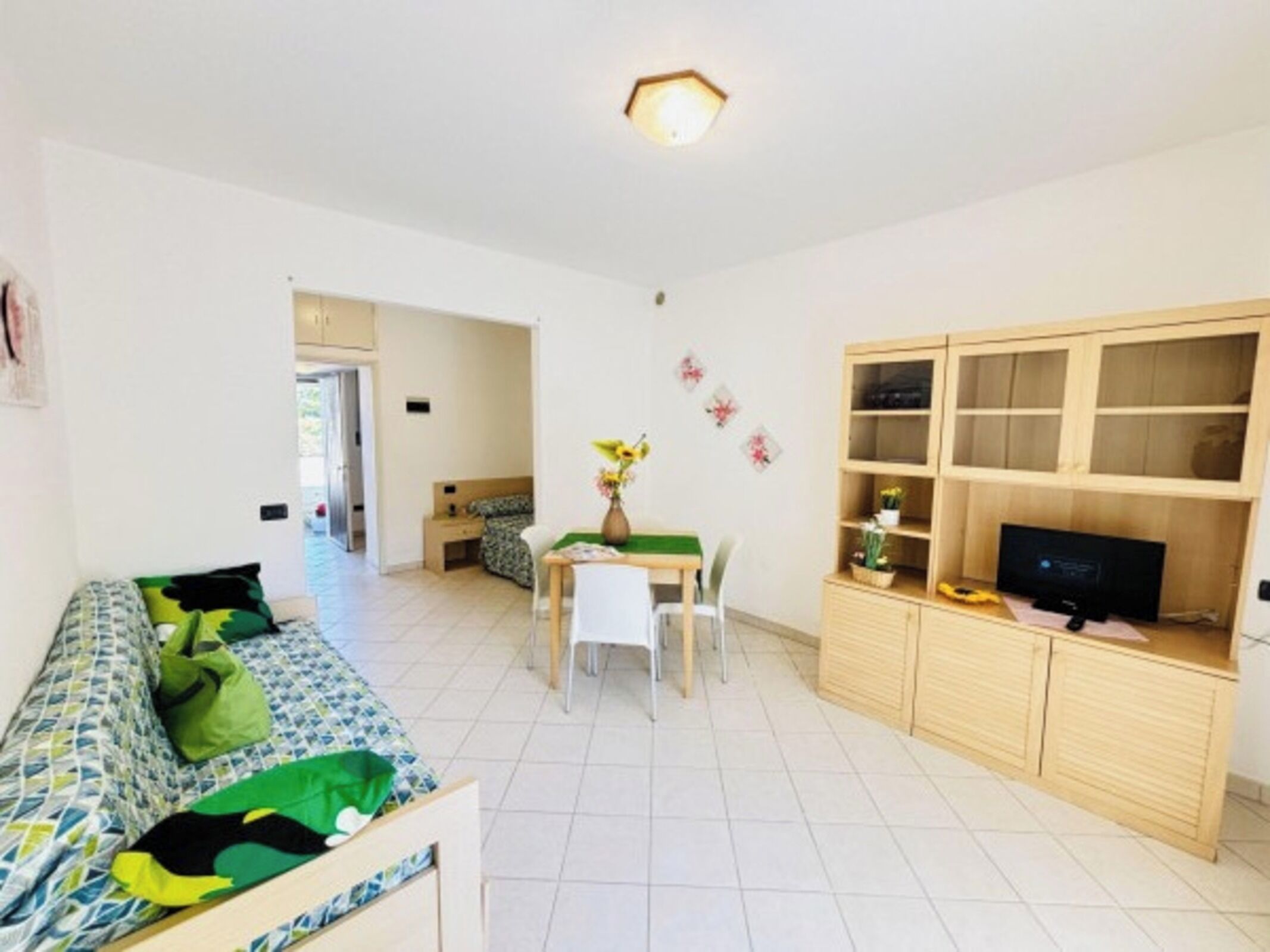 A compact living space with a sofa, a small dining table, a TV, and a cabinet.