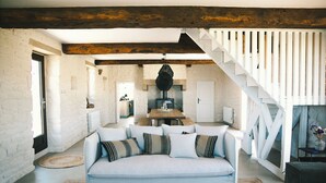 A spacious living area with a light blue sofa, a woven rug, and a wooden ceiling.