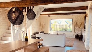 A spacious living area with a wooden bench, a white sofa, and a large window offering a view of the outdoors.