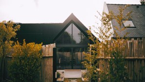 A modern house with a triangular roof, a glass door, and a wooden fence.