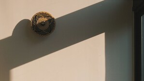 A modern living room with a sofa, a round side table, and a woven wall hanging.