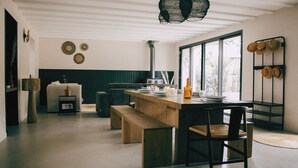 Una cocina moderna con una isla de madera, sillas negras y un amplio ventanal.