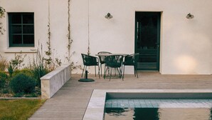 Una casa moderna con piscina, un patio amueblado al aire libre y un jardín cuidado.