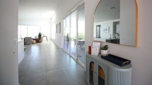 A modern hallway with a large mirror, a console table with a tray, and a sliding glass door leading to an outdoor area.