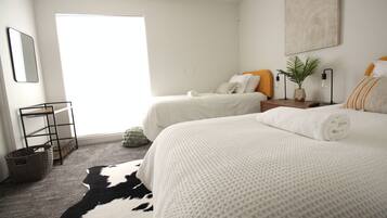 A modern hotel room with two beds, a large window, a cowhide rug, and a minimalist decor.