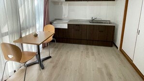 Une cuisine de taille réduite avec un coin repas, des meubles en bois et une fenêtre avec des rideaux.