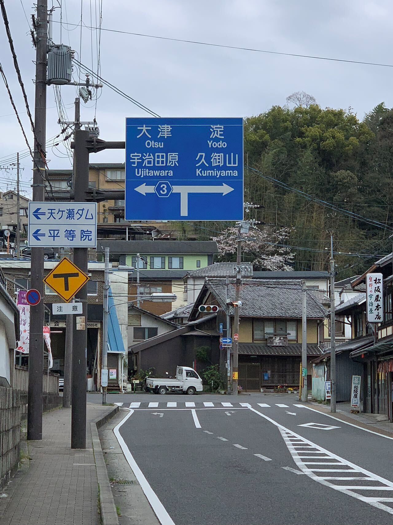 A street view with a directional sign indicating destinations such as Otsu, Yodo, Ujitawara, and Kumiyama.