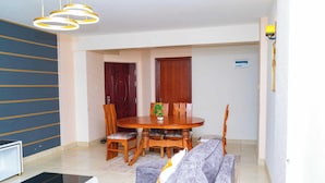 A dining area with a round wooden table, four chairs, and a small potted plant. - Lux Suites Clay City Heights Kasarani (Nairobi)
