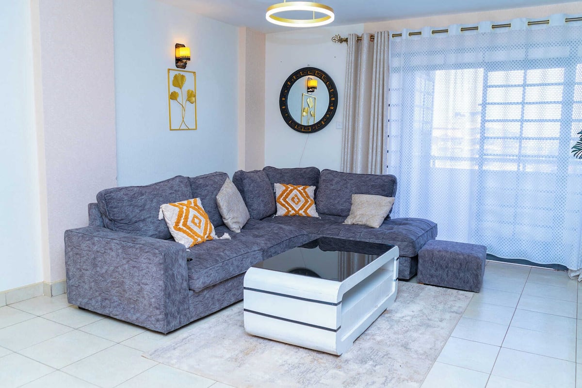 A modern living room with a grey sectional sofa, a white coffee table, and decorative pillows.