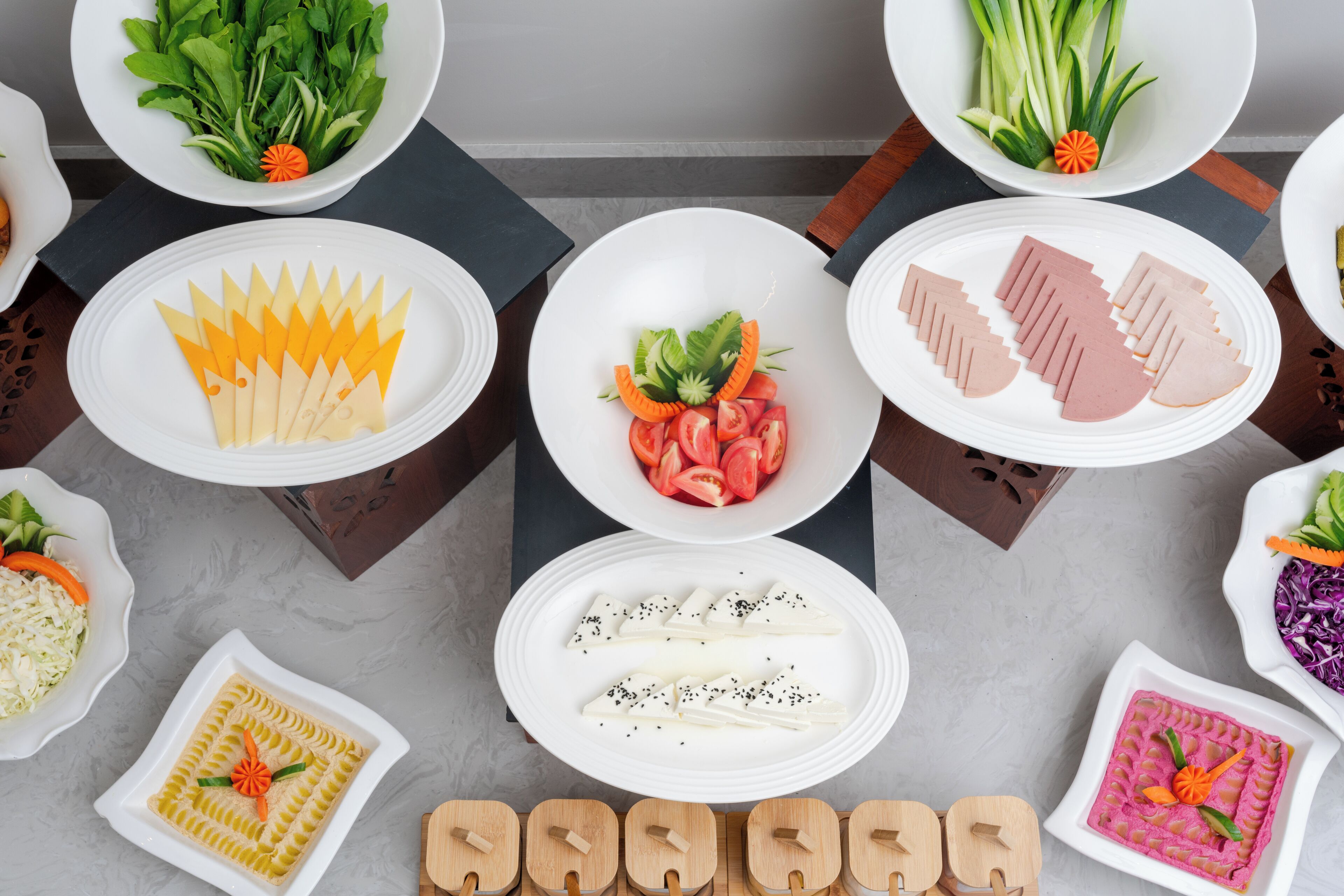 A table with various dishes, including salads, vegetables, and meat, arranged on white plates.