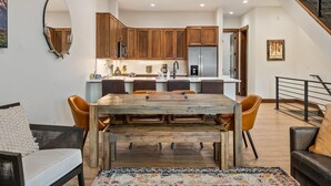 Eine moderne Küche mit Holzschränken, einem Edelstahlkühlschrank und einem Essbereich mit Holztisch und Stühlen.