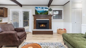 A living room with a fireplace, two sofas, a rug, and a view of mountains through the window. - Becca's Place 3 Bedroom Home by RedAwning (Pigeon Forge)