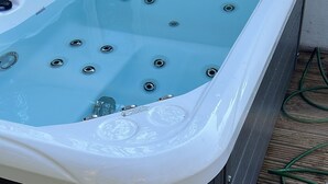 A hot tub with multiple jets, a control panel, and a wooden deck. - Turn up. Switch off Surrounded by trees with stream nearby, perfect escape for 2 (Windermere)
