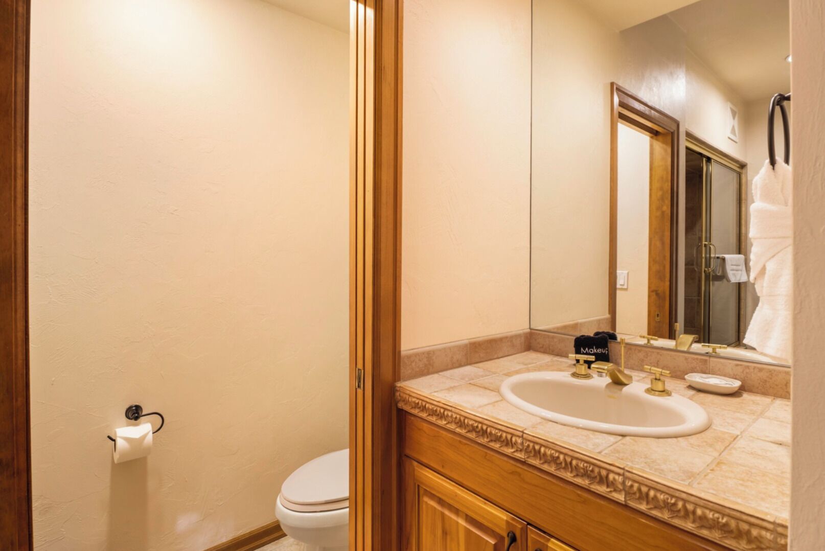 A bathroom with a toilet, sink, and mirror.