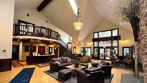 A spacious lobby with a high ceiling, a staircase, and a reception desk. - Summer 2026 Special - Amenities that include Pool, Steam Room, Sauna, Tennis, AC (sunriver)