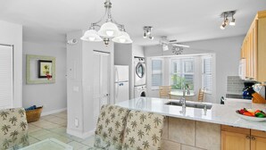 A modern kitchen with a central island, built-in appliances, and a seating area with patterned cushions. - THALIA'S RETREAT @ Duval Square 2bd/2ba townhome (Key West)