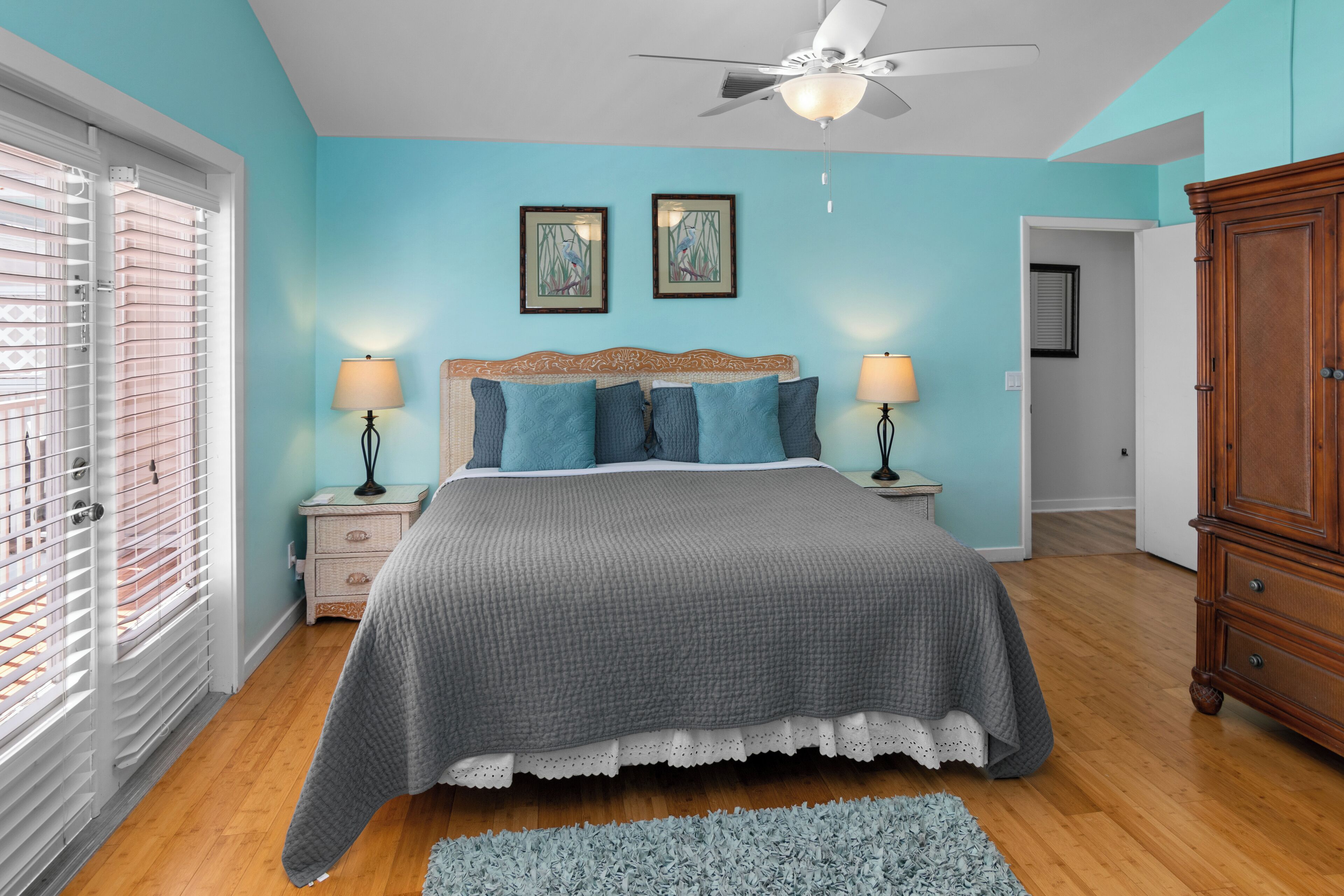 A bedroom with a bed, two bedside tables with lamps, a ceiling fan, and a wardrobe.