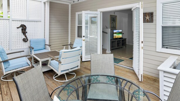 An outdoor patio with a glass table, chairs, and a seating area. - THALIA'S RETREAT @ Duval Square 2bd/2ba townhome (Key West)