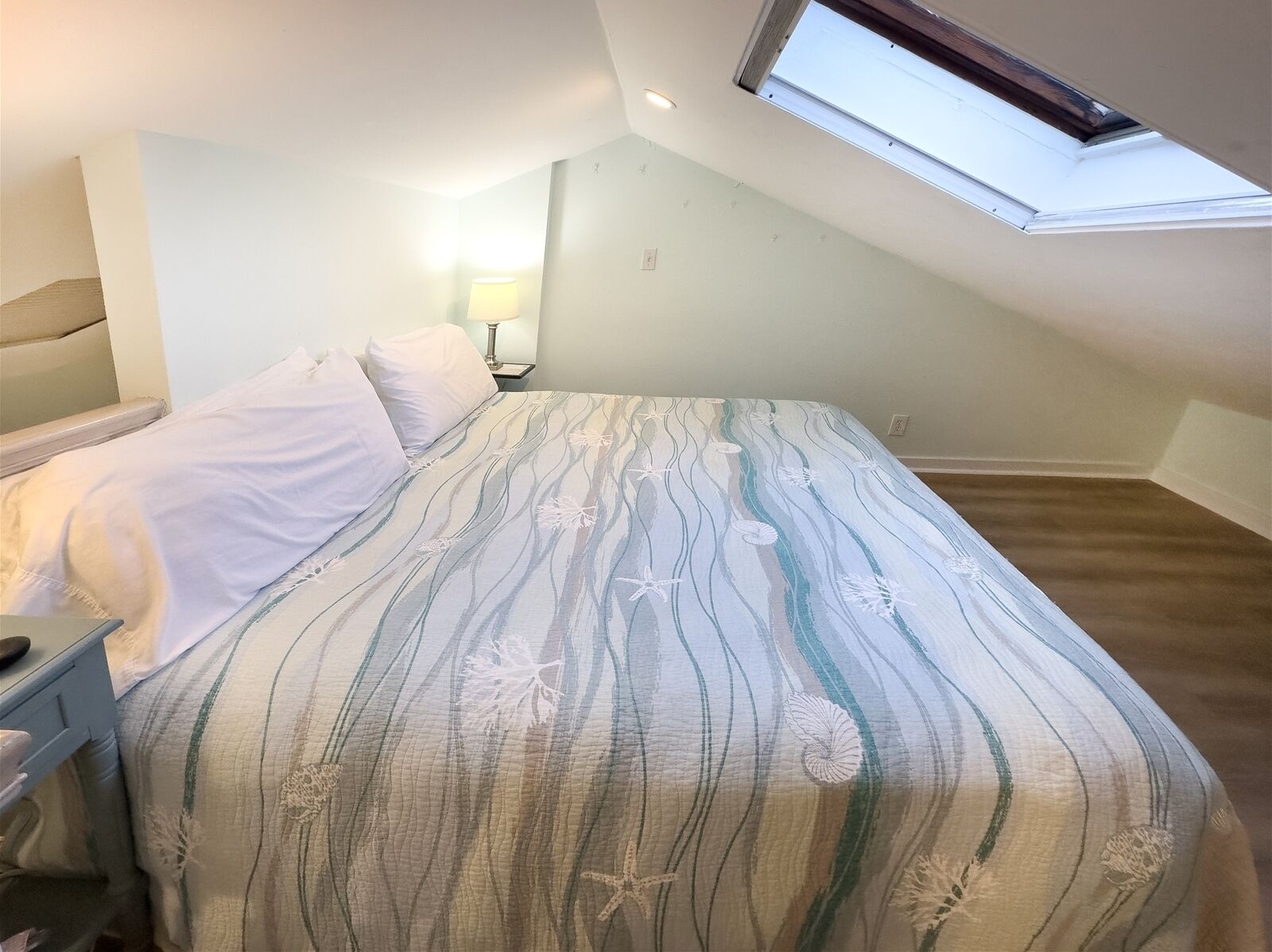 A bedroom with a sloped ceiling and a skylight.