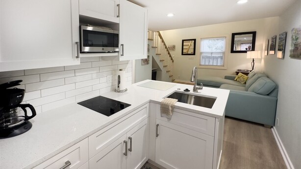 A compact kitchen with white cabinetry, a built-in microwave, a sink, and a coffee maker. - Rent at PORCHSIDE PARADISE - Steps to Duval (Key West)