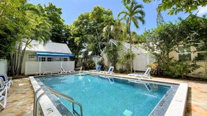 Une piscine à l’eau d’un bleu cristallin, entourée d’une végétation luxuriante et de palmiers.
