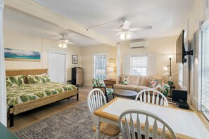 A well-lit room with a bed, a dining table, chairs, a sofa, and a ceiling fan. - Hollinsed House Studio - Great Location!! (Key West)