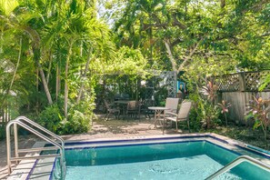 A backyard with a swimming pool, patio furniture, and a wooden fence. - Hollinsed House Studio - Great Location!! (Key West)