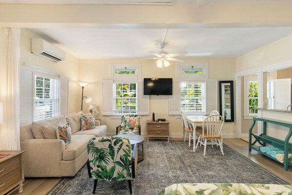 A living room with a sofa, a coffee table, a TV, and a dining area with a table and chairs.