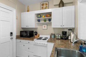 A kitchen with white cabinets, a stove, a microwave, a toaster, and a sink. - Hollinsed House Studio - Great Location!! (Key West)