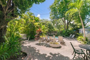 A patio area with a pool table, lounge chairs, and a decorative fountain.
