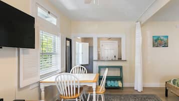 A dining area with a table, chairs, and a television mounted on the wall.