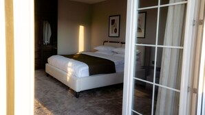 A bedroom with a bed, a bedside table, a chair, and a window. - Downtown Apartments (Pristina)