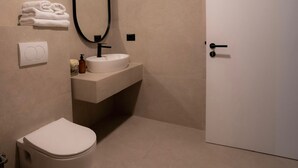 A modern bathroom with a toilet, sink, and a large mirror. - Downtown Apartments (Pristina)