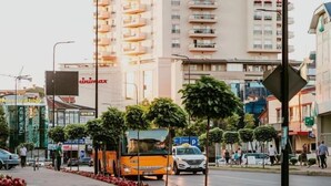 A multi-story building with a Coca-Cola sign, surrounded by a street with cars and pedestrians. - Downtown Apartments (Pristina)