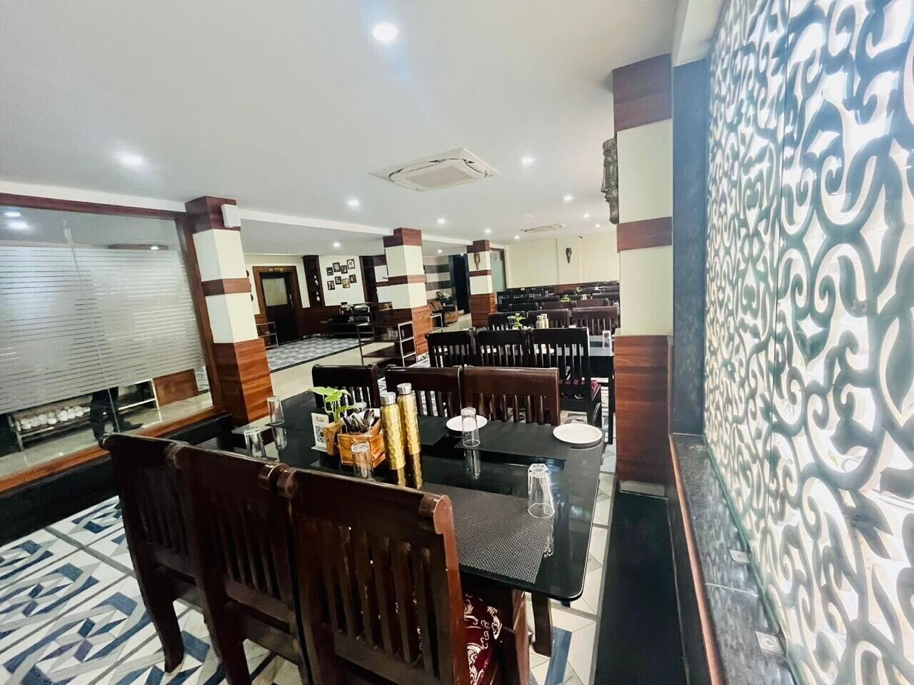 A restaurant with multiple tables and chairs, a patterned wall, and a tiled floor.