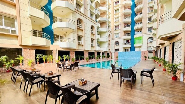 A multi-level hotel with a central swimming pool, outdoor seating area, and potted plants. - Hotel Four Waves (Puri)