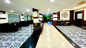 A hotel lobby with a central reception desk, seating area, and a patterned floor. - Hotel Four Waves (Puri)
