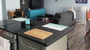 A modern kitchen with a central island, built-in oven, and a dining area with a sofa and table.