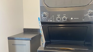 A compact washer and dryer unit with control knobs and a small cabinet.