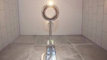 Une salle de bain équipée de toilettes, d’un miroir et d’un luminaire fixé au mur.