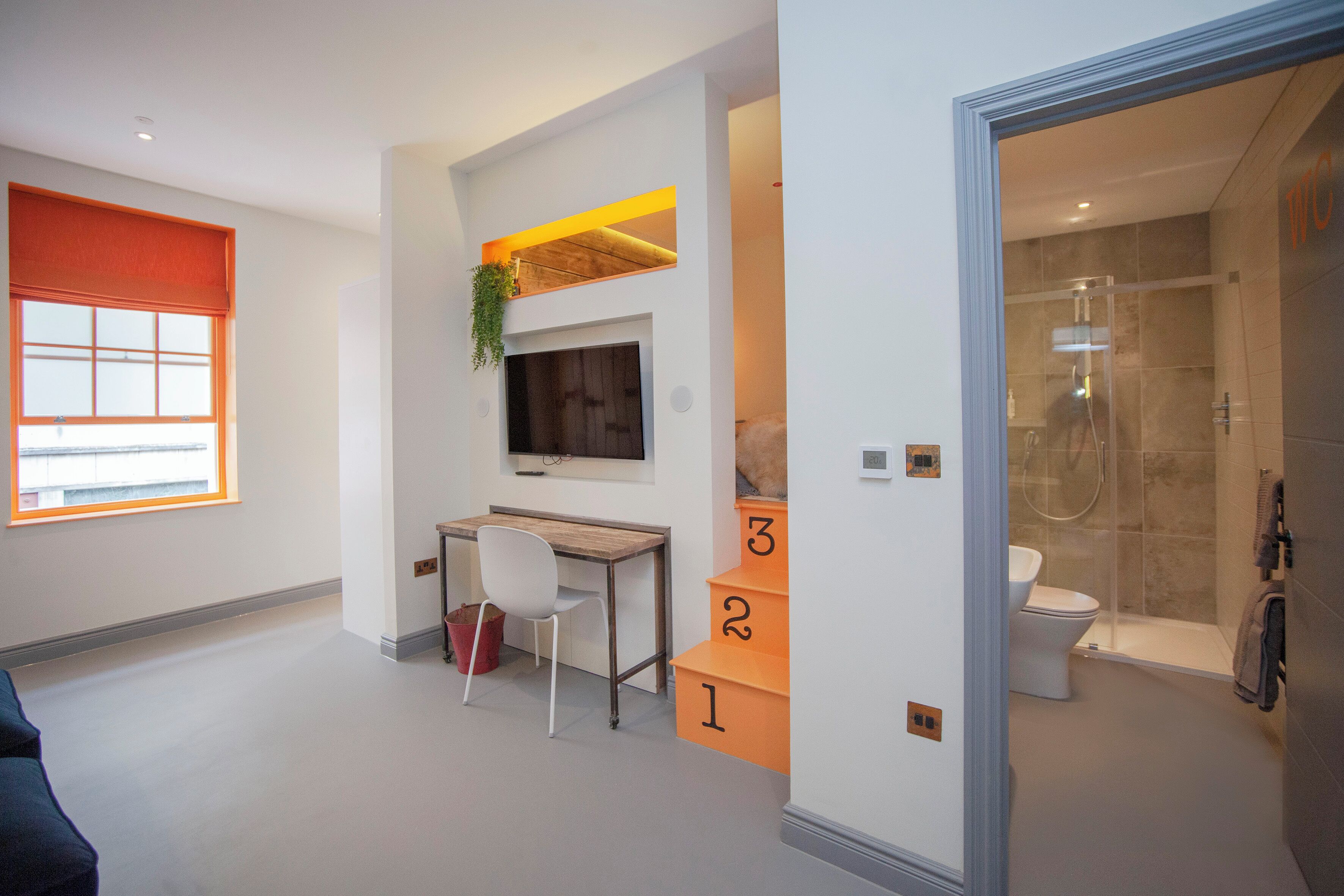 A modern bathroom with a glass shower enclosure, a toilet, and a sink.
