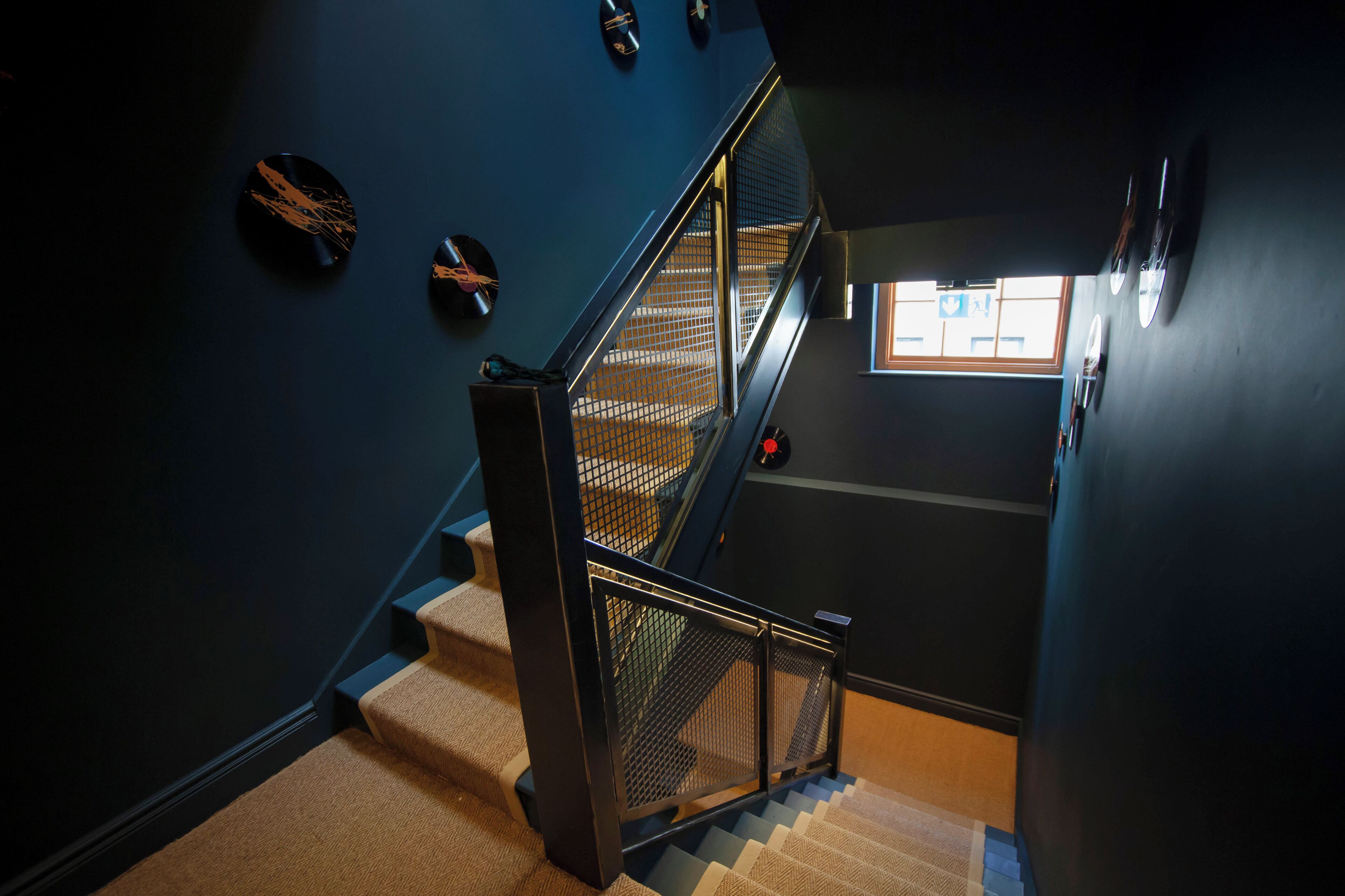A staircase with a metal railing, carpeted steps, and a window at the top.