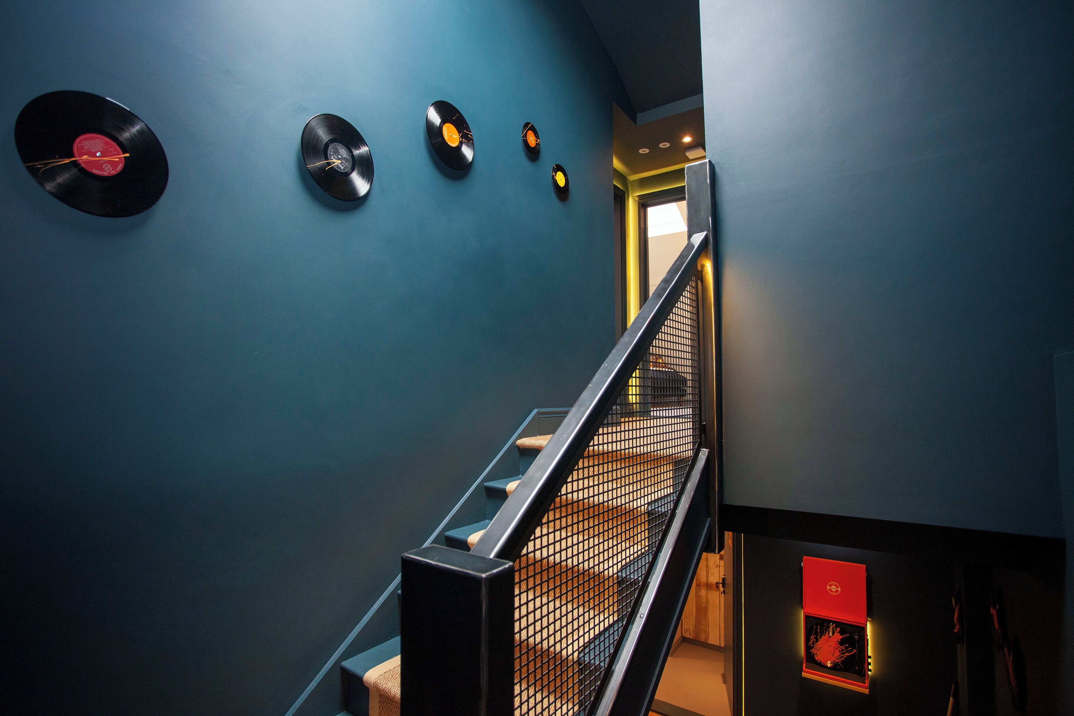 A staircase with a metal railing and a blue wall.