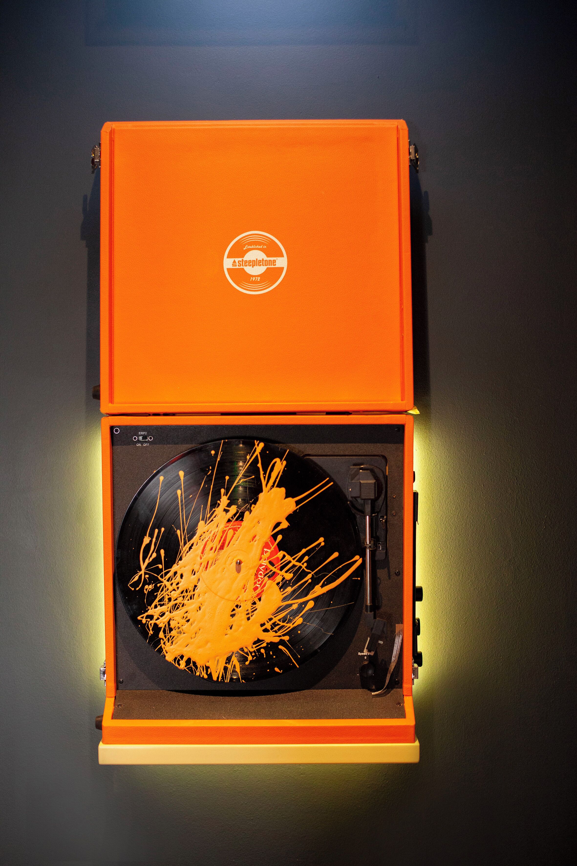 A turntable with a record inside a bright orange case.